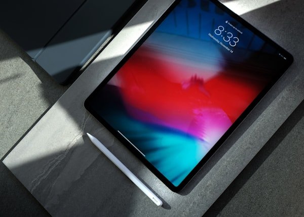 An iPad Pro with Apple Pencil on a stone surface.