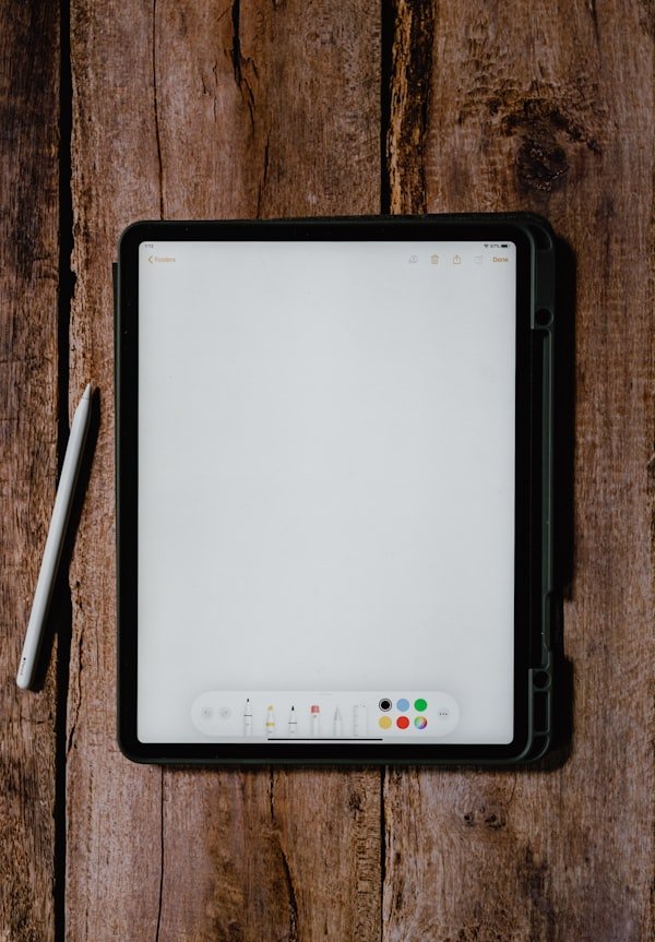 Digital tablet and stylus on a rustic wooden table.
