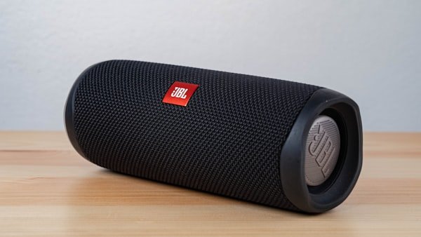 Black JBL portable Bluetooth speaker on a wooden table.